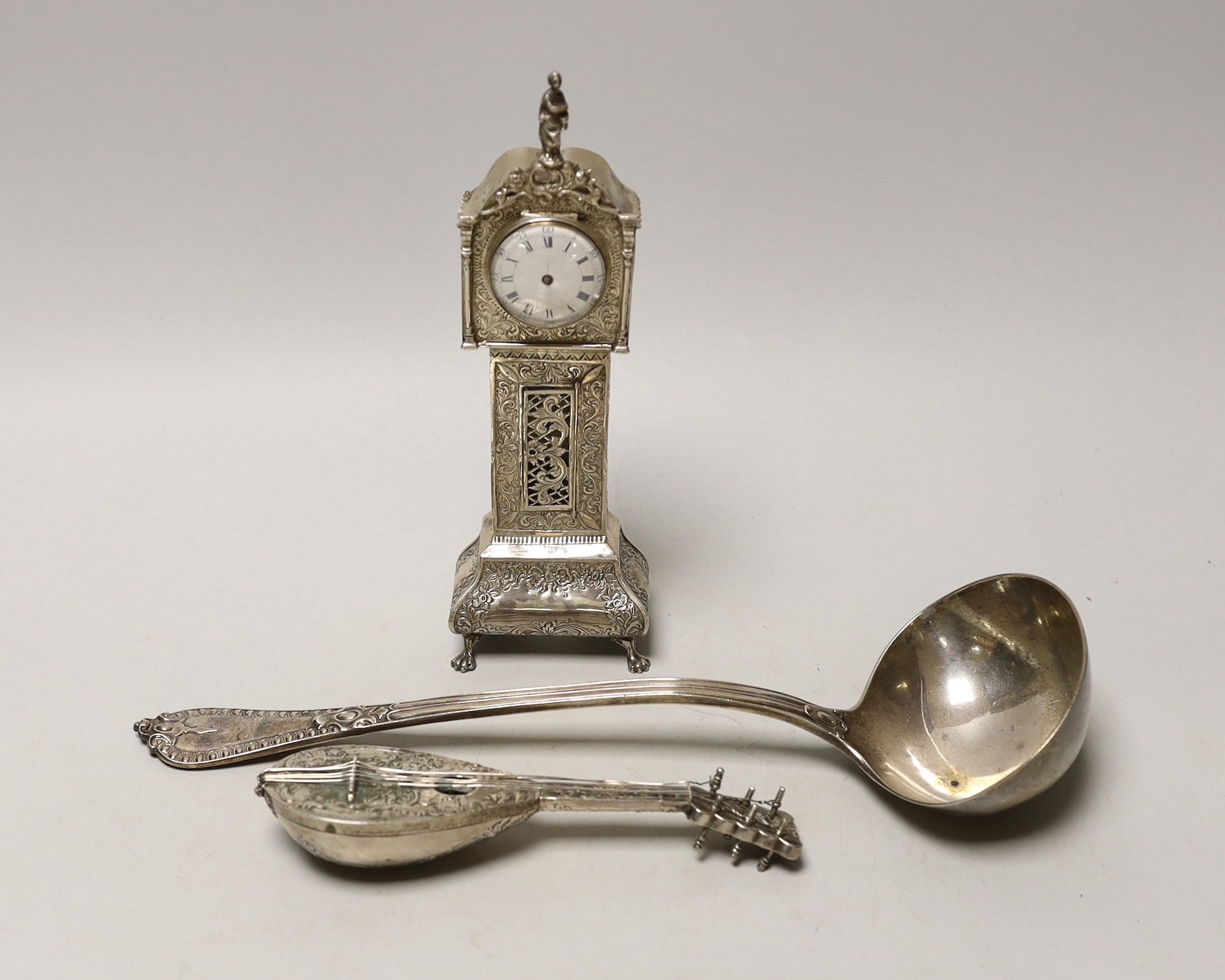 A Dutch white metal miniature longcase clock, 23.8cm, a similar model of a mandolin and a Victorian silver soup ladle by George Adams.